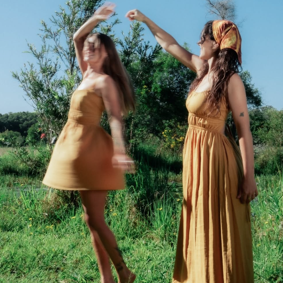 Two women twirling around in Oakie the Label dresses with trees in the background