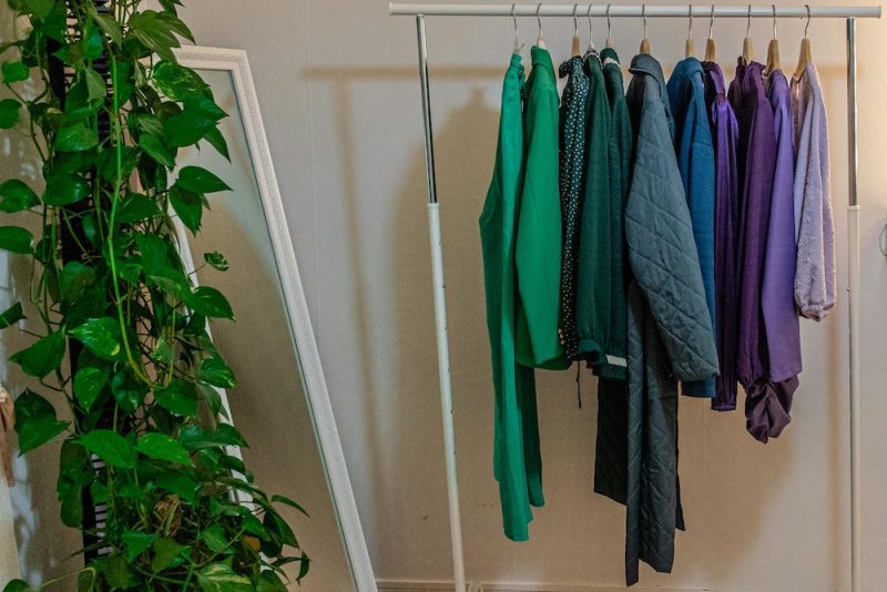 Rack of clothing with a hanging plant in one corner