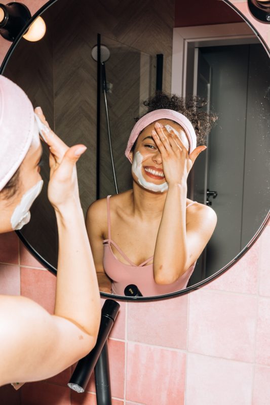 Woman looking into the mirror with natural beauty products on her face