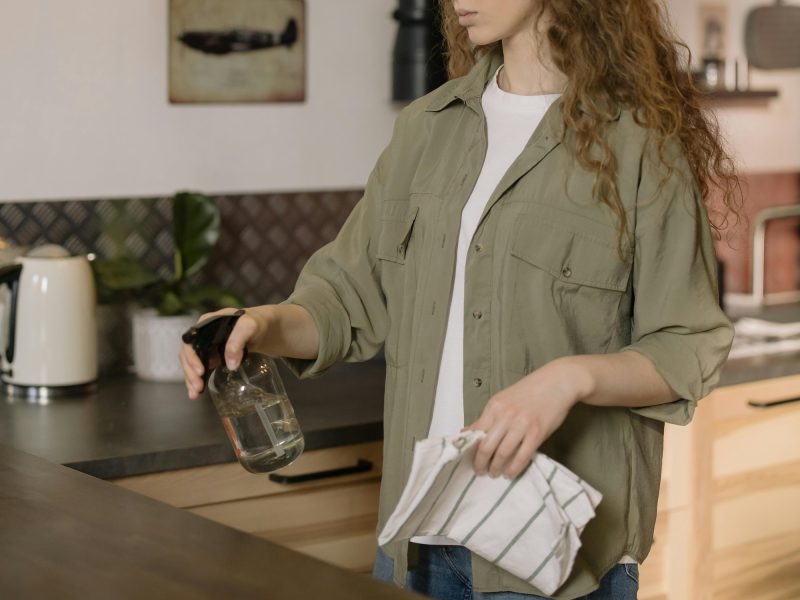 Person using a sustainable cleaning product on their kitchen bench top.